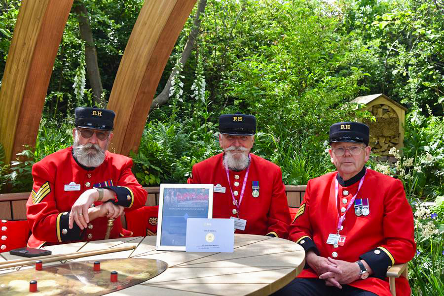 Chelsea Pensioners sit in the award winning garden with their gold medal certificate proudly on display