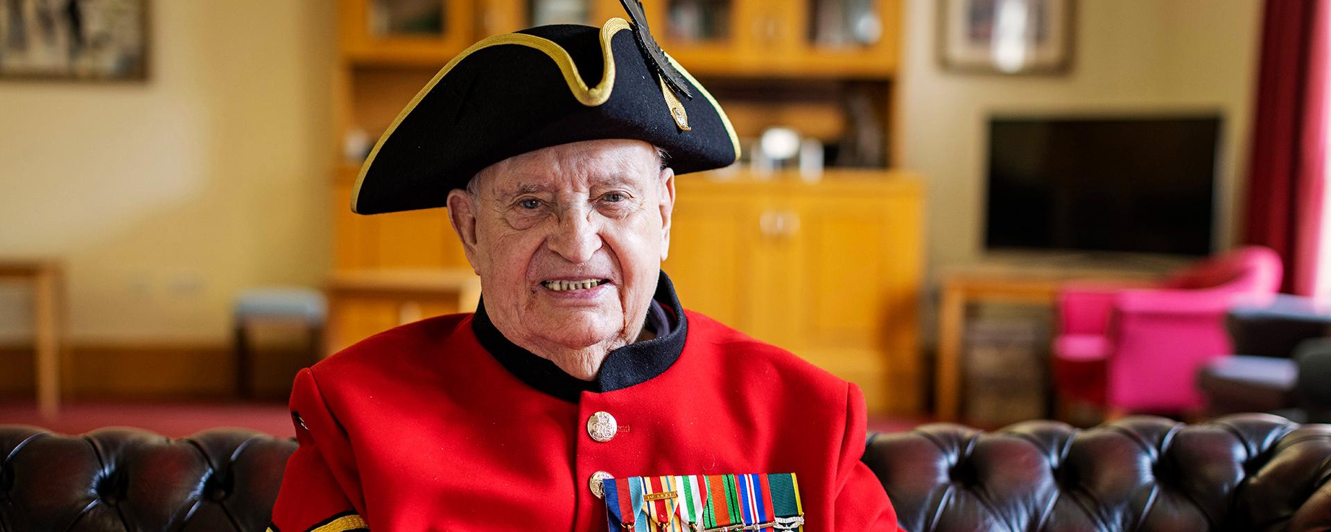 John G Morris, Chelsea Pensioner sits in the MTI wearing iconic scarlet uniform and tricorn hat.